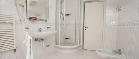 A modern bathroom with a shower, sink, toilet, and a towel rack.