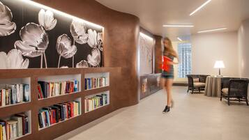 Una biblioteca moderna con estanterías, un área de descanso y un ventanal grande.