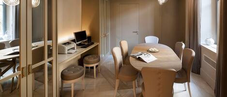 Un espace repas moderne avec une table ronde, six chaises, un ordinateur sur un bureau et un grand miroir.