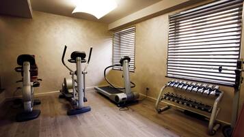 Una palestra in casa con tapis roulant, ellittica e panchetta per pesi.