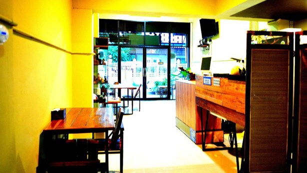 A room with a wooden table and chairs, a bench, a counter, and a view through a glass door. - Home at Samlan Soi 1 (Chiang Mai)