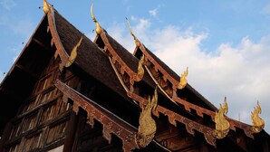 A traditional wooden building with ornate golden decorations and a steeply pitched roof. - Home at Samlan Soi 1 (Chiang Mai)