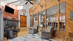A spacious living room with a fireplace, comfortable seating, and a large TV. - Riley's Retreat  Hot Tub and air conditioning!   (Rapid City)