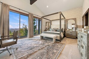 A spacious bedroom with a large bed, a sitting area, and a view of the outdoors.