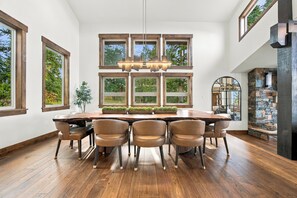 A dining area with a large wooden table, six chairs, and a modern chandelier.
