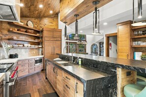 Une cuisine moderne avec des meubles en bois, un plan de travail en marbre et des luminaires suspendus.