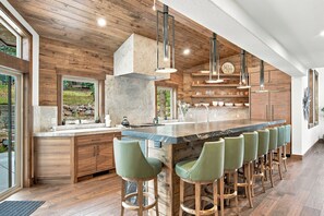 Une cuisine moderne dotée d’un grand îlot central, de tabourets de bar et de meubles de rangement en bois.
