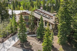 Une maison à deux étages, dotée d’un toit en pente, entourée d’une forêt dense.