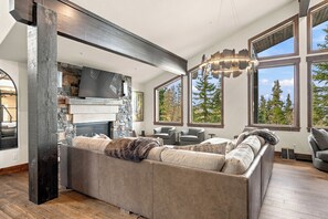 Un salon moderne avec une cheminée en pierre, de grandes fenêtres et un coin salon confortable.