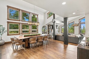 Une cuisine spacieuse avec un grand îlot central en bois, de nombreuses fenêtres et un mur d’accent en pierre.