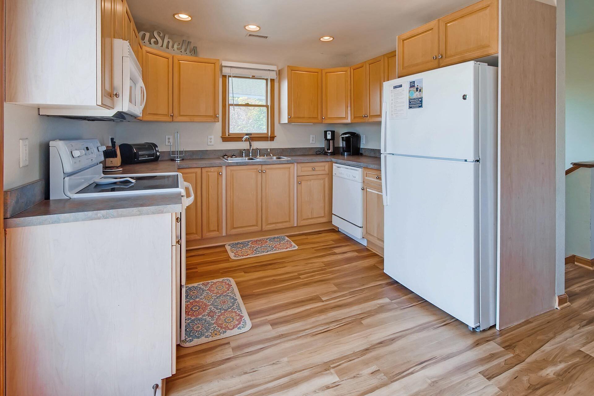 A kitchen with wooden cabinets, a white refrigerator, a stove, and a coffee maker.
