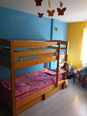 Una cama litera con colchón rosa, estructura de madera y pared azul con adornos de mariposas.