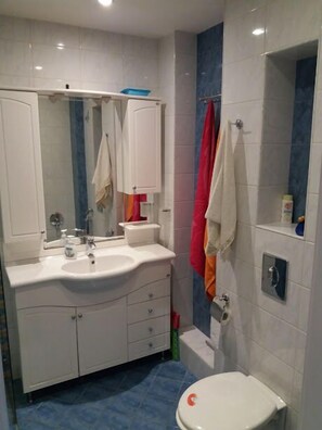 A bathroom with a white sink, mirror, and white toilet. There are towels hanging on the wall and a shower curtain. - Varna Seaview Residence (Varna)