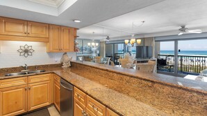A kitchen with granite countertops, wooden cabinets, and a view of the ocean. - 214- Adventure to WHITE SANDS and sparkling waters! Destin Beach Club (Destin)