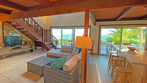 A spacious living area with a sofa, a TV, and a staircase leading to a balcony.
