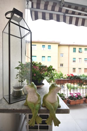 A balcony with two frog statues, a hanging lantern, and potted plants. - B&B Agli Orti (Verona)