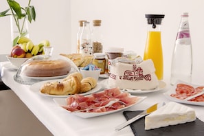 A breakfast table with croissants, ham, cheese, fruit, and juice. - B&B Agli Orti (Verona)