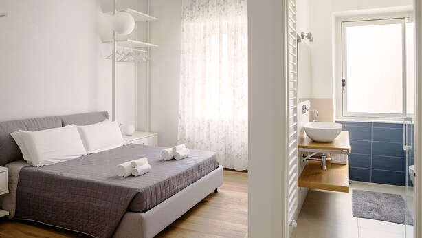 Un dormitorio moderno con una cama grande, una mesita de noche, un armario y un baño con lavabo e inodoro.
