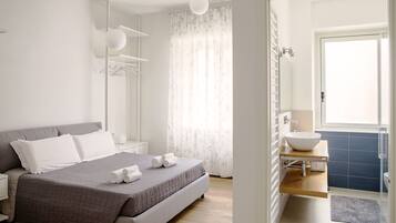 Une chambre moderne avec un grand lit, une table de chevet, une armoire et une salle de bain équipée d’un lavabo et de toilettes.