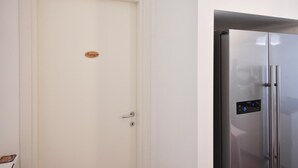 Una puerta blanca cerrada con una pequeña placa y un refrigerador de acero inoxidable moderno con panel de control digital.