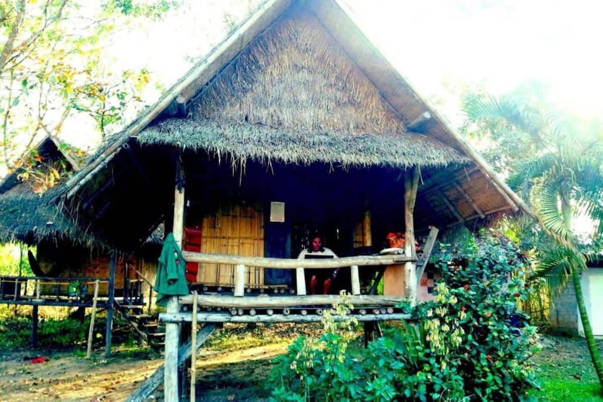 A thatched-roof hut with a wooden porch and a wooden door.