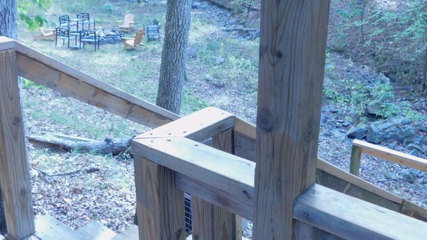 Une terrasse en bois offrant une vue sur une zone boisée et aménagée avec du mobilier d’extérieur.