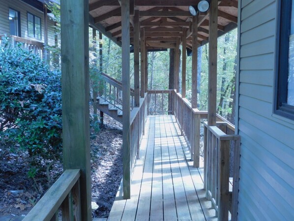 A wooden deck leading to a house with a covered porch.