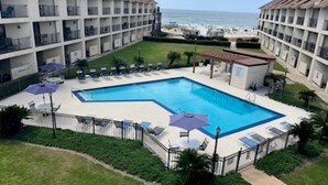 Un hôtel doté d’une piscine entourée de chaises longues et de parasols, d’un jardin clos et offrant une vue sur la plage.