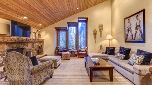 Un salon chaleureux avec une cheminée, un plafond en bois et de grandes fenêtres.