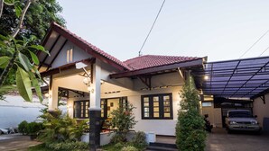 A house with a tiled roof, a covered porch, and a car parked in the driveway. - Ndalem Sarengat (Yogyakarta)