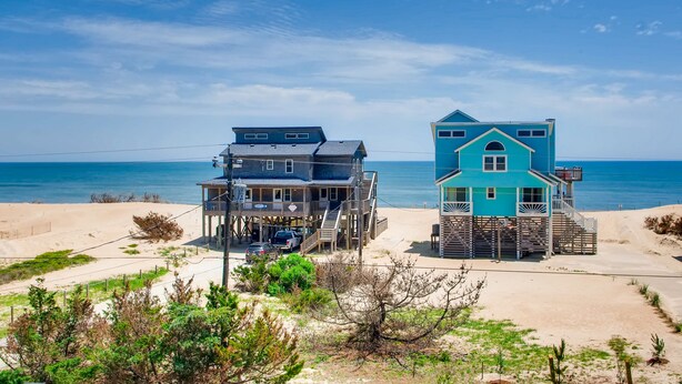 A beachfront property with two multi-story buildings, a sandy beach, and the ocean in the background. - Semi-Oceanfront Dog Friendly Avon Home w/ Private Pool, Hot Tub, and Game Room (Avon)