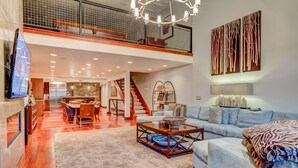 A spacious living area with a high ceiling, a staircase, a dining area, and a large window. - Luxury in Central Location. Shuttle outside door! Pool Table, Hot Tub, Ultra Lux (Park City)