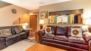 A living room with a brown leather sofa, a wooden coffee table, and a patterned rug. - Heart of PC! 2 blocks from lift! Shuttle to Main in 3 minutes! Cozy w/ hot tub! (Park City)