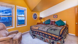 A bedroom with a large bed, two windows with snow views, a chair, and a wall-mounted clock. - Heart of PC! 2 blocks from lift! Shuttle to Main in 3 minutes! Cozy w/ hot tub! (Park City)