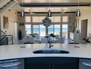 Een moderne keuken met een centraal eiland, grote ramen en uitzicht op de oceaan.