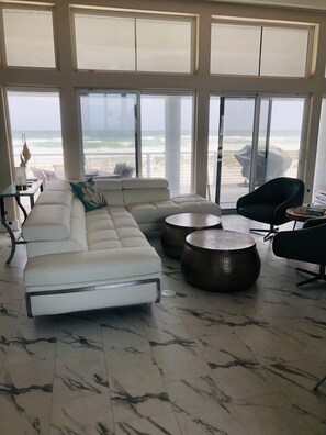 Relax in this spacious living room with a sofa, two coffee tables, and a view of the ocean and beach.