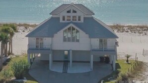 A beachfront house with a central bay window, a covered porch, and a driveway leading to the entrance. - Sol LaRu- direct Gulf/BeachFront White Sand Beaches Contempory Home (Pensacola Beach)