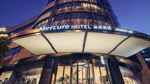 L’extérieur de l’hôtel Mercure présente une architecture moderne, avec une entrée imposante et une enseigne lumineuse bien visible.