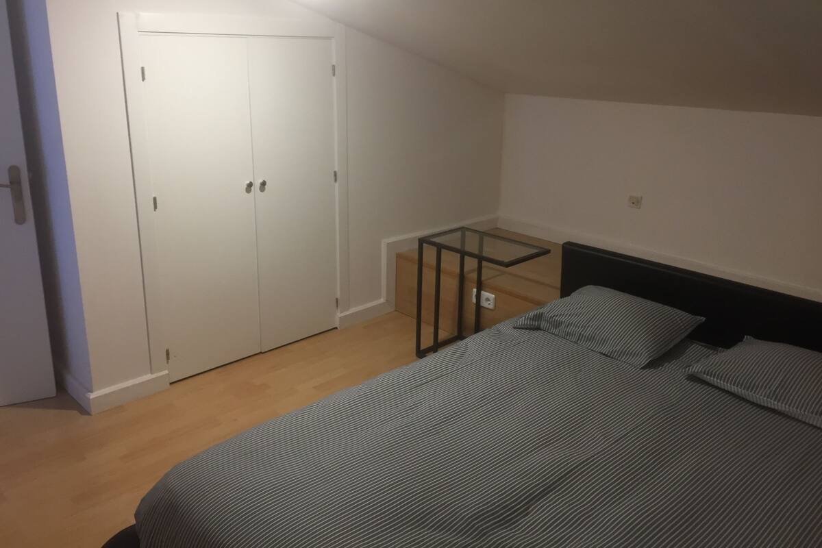 A bedroom with a bed, a wardrobe, and a small table.