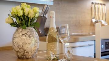 Een marmeren vaas met gele rozen, een fles Villa Strandblick champagne en twee glazen op een aanrecht.