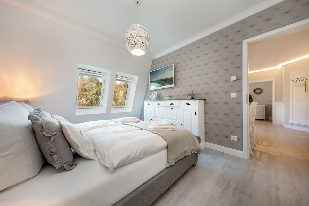 A bedroom with a bed, bedside tables, a dresser, and a window.