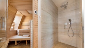 Un baño moderno con un banco de madera, una ducha con cabezal de ducha de mano y un termostato visible en la pared.