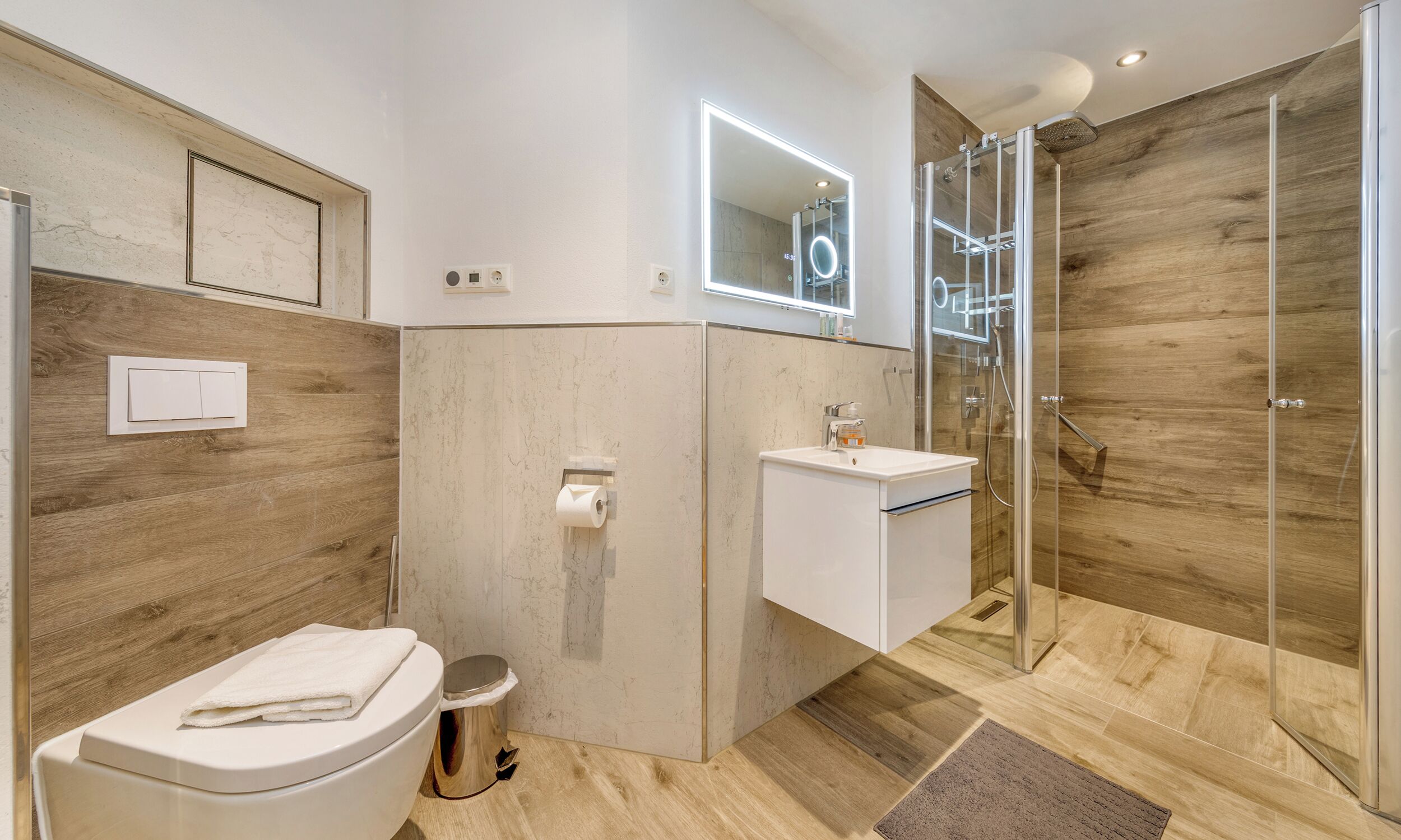 Un baño moderno con inodoro, lavamanos y ducha.