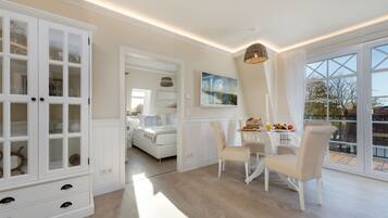 Un espacio amplio con zona de comedor, un armario blanco con puertas de cristal y un ventanal que ofrece vistas al exterior.