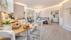 Una cocina moderna con comedor, que incluye una mesa con pan, frutas y bebidas.