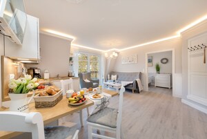 Eine moderne Küche mit Essbereich, ausgestattet mit einer Frühstücksvorrichtung mit Brot, Früchten und Getränken.