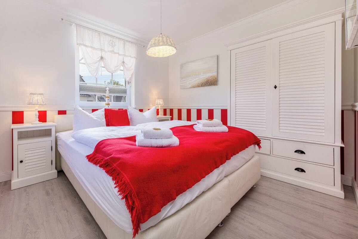 A bedroom with a bed, two bedside tables, a wardrobe, and a window with curtains.