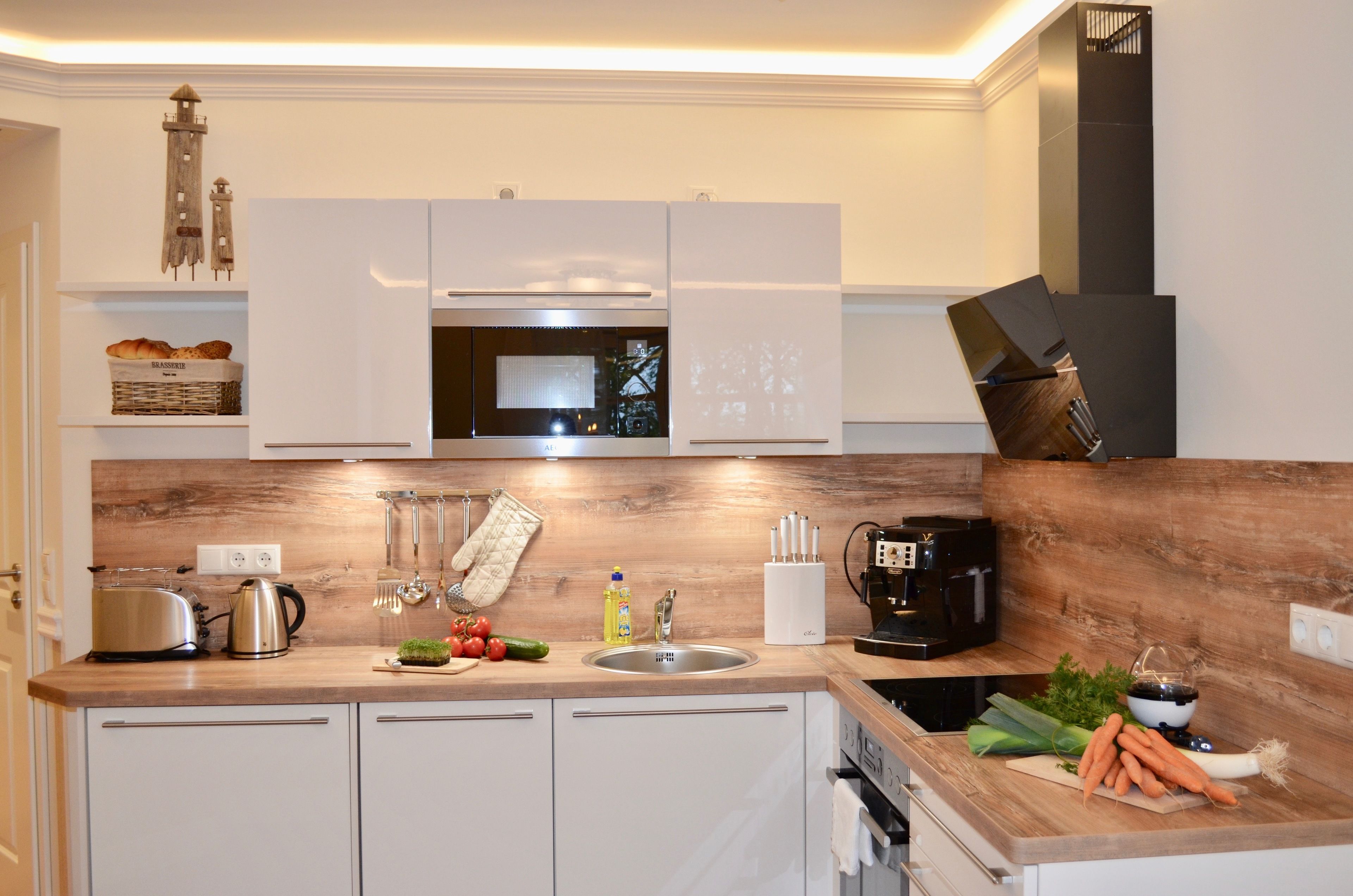 A modern kitchen with white cabinets, a wooden countertop, a microwave, a coffee maker, and various kitchen utensils.