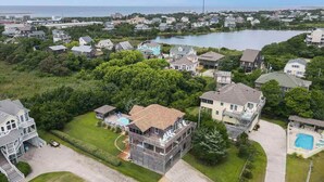 Vue aérienne d’un quartier résidentiel avec des maisons, une piscine et une grande étendue d’eau en arrière-plan.