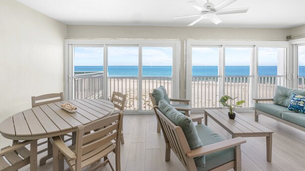 A balcony with a view of the beach, a dining table, and seating area. - Sparkling Views from this two bedroom, two bathroom Gulf Front Sandy Bend 8 (Sanibel)